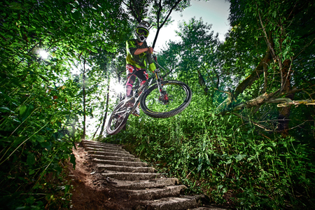 Moscow, Russia - August 31, 2017: Jump and fly on a mountain bike. Rider in action at mountain bike sport. Biker riding in forest. Cool athlete cyclist on a bike. MTB biking.のeditorial素材