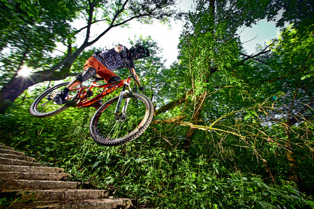 Moscow, Russia - August 31, 2017: Jump and fly on a mountain bike. Rider in action at mountain bike sport. Biker riding in forest. Cool athlete cyclist on a bike. MTB biking.のeditorial素材