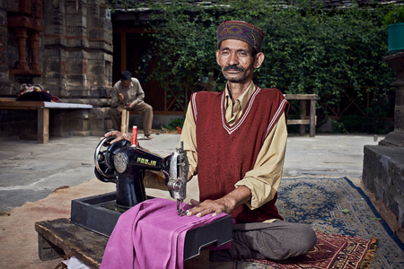 Naggar, INDIA - JULY 17: Traditional Indian tailor. Posing for photography. July 17, 2013 in Naggar, Kullu Valley, Himachal Pradesh, India.のeditorial素材