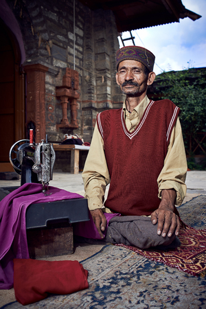 Naggar, INDIA - JULY 17: Traditional Indian tailor. Posing for photography. July 17, 2013 in Naggar, Kullu Valley, Himachal Pradesh, India.のeditorial素材