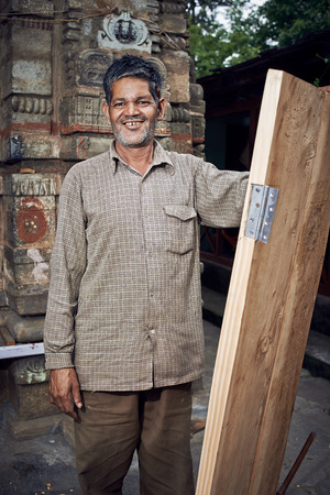 Naggar, INDIA - JULY 17: Indian carpenter made a door. Smiling and posing for photography. July 17, 2013 in Naggar, Kullu Valley, Himachal Pradesh, India.のeditorial素材