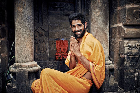 Naggar (Kullu Valley), North India - July 2013. Smiling Indian Brahmin. sitting near the temple of Lord Krishna. Hands folded in namaste mudra.のeditorial素材