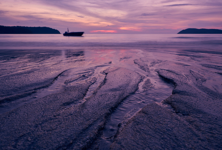 Sunset over Pantai Cenang beach with pink colours, blur background and silhouette of boat. Langkawi, Malaisiya.の写真素材