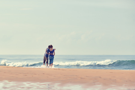 Young Couple standing on beach and looking to a sea. A man is showing his hand in the sea.の写真素材