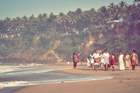 Kerala, India - Nov 30, 2017: Indian family - womans, mans and childs in traditional clothes taking a walk at beautiful sunny morning at Varkala beach.のeditorial素材