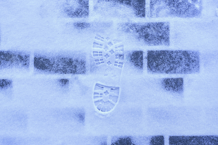 Shoe prints in fresh snow on brick floor at sunny day. Footprint snow. Hard shoe footprint on white snow surface in winter.の写真素材
