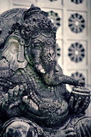 An old Asian statue of Ganesha god stands in the garden of a temple - Ubud, Bali, Indonesia.の写真素材