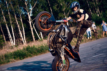 Moscow, Russia - Jul 12, 2020: Moto rider making a stunt on his motorbike. Stunt motorcycle rider performing motorcycle show. Motorcyclist making doing a difficult and dangerous stunt on his motorbike