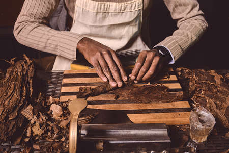 Process of making traditional cigars from tobacco leaves with hands using a mechanical device and...