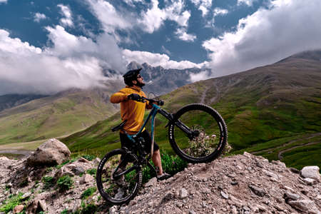 Elbrus, Kabardino-Balkaria, Russia - August 2017: Mountain biking in Elbrus. Cyclist on the top of a hill and enjoying view of the mountains. MTB bicycle rider standing at cliff.のeditorial素材