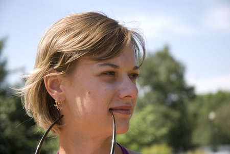 Outdoor portrait of one young clam girl holding glasses