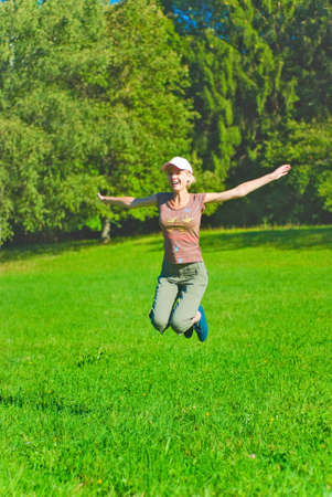 Beautiful young woman jumping over the green grass