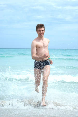 Happy man running from ocean wavesの写真素材