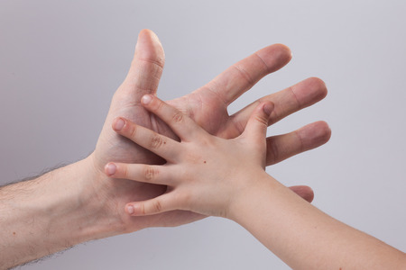 adult and child's hand touching help tendernessの写真素材