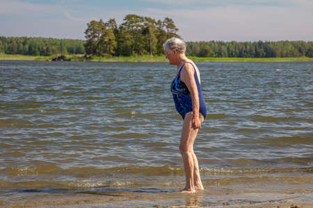Old woman, bathes. Beach, sunny summer day. High quality photoの写真素材