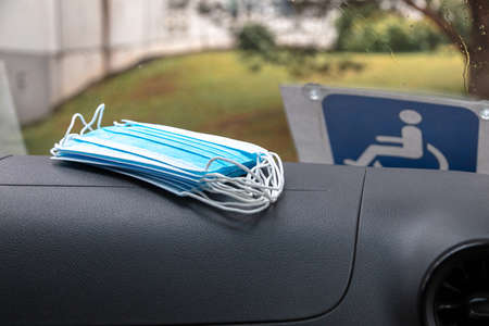 In the car, there are medical masks on the torpedo. Disabled sign on the windshield. High quality photoの写真素材