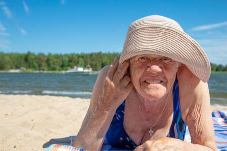 Old woman, in a summer hat and a swimsuit on the beach. Sunny, summer day by the sea. Concept: healthy lifestyle. High quality photoの写真素材