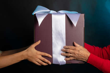 Hands of a young and old woman hold a gift. Happy New Year. High quality photoの写真素材