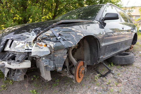 wreckage of modern car after accident used for parts out side front detailed closeup view of damaged auto vehicle after crash on asphalt road with many parts removed transportation concept background. High quality photoの写真素材