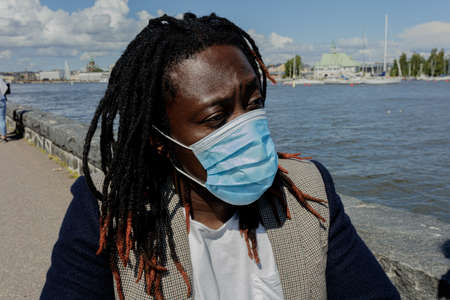 A young African man wears a medical mask to protect himself from the coronavirus outbreak. Close-up . A man in a wheelchair. Summer sunny day. High quality photoの写真素材