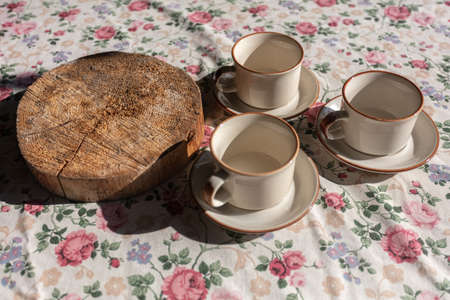 There are three empty tea mugs and a wooden stand on the table. photo, view from the top, open air....