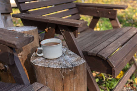 Cup with tea and wooden chairs, outdoors. High quality photo