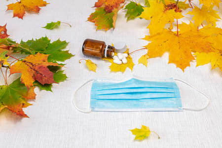 Still life on a white background maple leaves, glass bottle and pills, medical mask, concept, take care of the fall, health. High quality photoの写真素材
