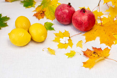 Maple leaves, lemons and pomegranates on a white background. Autumn vitamins concept. High quality photoの写真素材