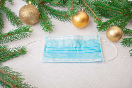 Medical mask, Christmas balls, green spruce branches. New year concept during a pandemic, protect yourself from coronavirus, there is a place for text, on a white background. High quality photoの写真素材