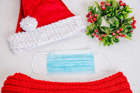 Christmas hat, medical mask, red scarf and Christmas wreath on a white background. the concept of...