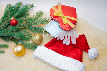 The gift box contains a medical mask and latex gloves, a spruce branch and Christmas decorations and...