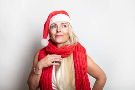 A blonde woman, long hair in a gnome cap is thinking about a gift. Concept gifts for the New Year. High quality photoの写真素材