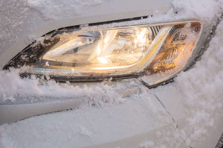 The headlight of the car is covered with snow. High quality photo