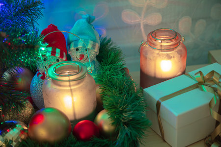 Christmas decorations by the tree and a gift in a white box. Burning candles. High quality photoの写真素材