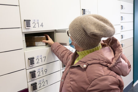 Espoo, Finland January 9, 2021 Post office woman picks up a parcel. she is wearing a medical mask in...