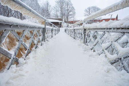 A snow-covered, icy bridge over a waterfall in the Old City in Helsinki, Finland. High quality photo