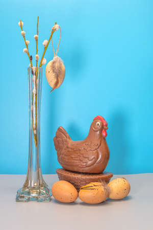 Chocolate chicken and egg, willow branches in a vase on a blue background. Concept, Easter, congratulations, levitation, There is a place for text. High quality photoの写真素材