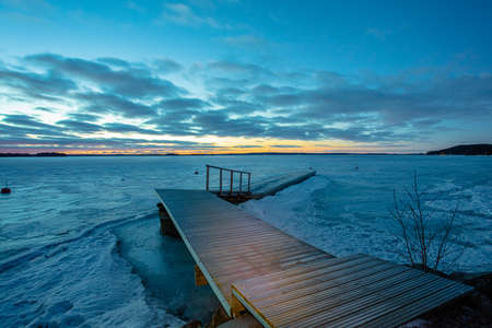 Winter sunrise over a lake covered with ice. Moon in the blue sky. Finland, Scandinavian natureの写真素材