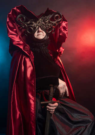 Fabulous creature, historical character, fantasy queen, witch, in costume. Woman, model after 60, in the studio, dark backgroundの写真素材