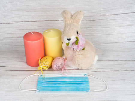 Colorful eggs around the bunny and candles. Happy Easter. Rabbit and medical mask, time of coronavirus covid19. Health care, holiday, mask stay safe. Spring season. Happy Easter banner light background.の写真素材
