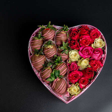 Heart of roses and strawberries on a dark background. Congratulations concept, there is a place for textの写真素材