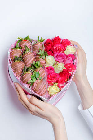 Heart of roses and strawberries in hands on a white background. Congratulations concept, there is a place for textの写真素材