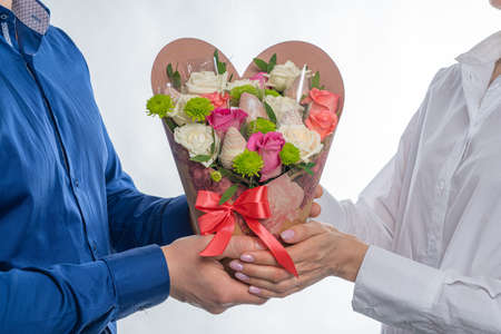 Edible bouquet of sweets, flowers and glazed strawberries On a light background. Cropped photo of a man giving a beautiful gift to a woman. Holiday conceptの写真素材