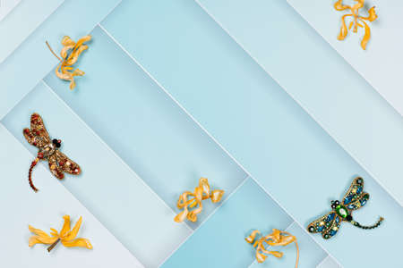 On a blue, abstract background, decorative ornaments of dragonflies and dry yellow flowers. There is room for text.の写真素材