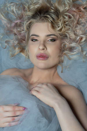 Gorgeous woman, bland, sexy with curly hair lying in bed,の写真素材