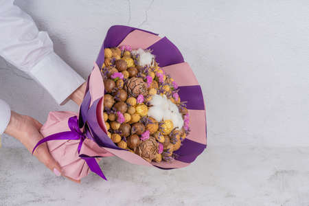 Sweet bouquet of nuts and flowers in hands, close-up The concept of the holiday, congratulations.の写真素材
