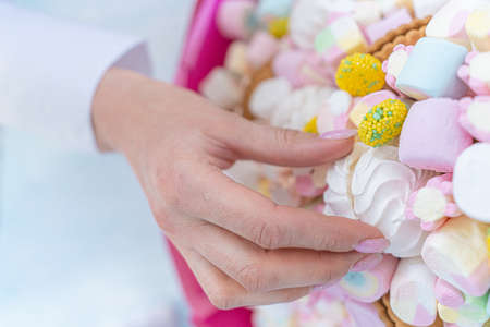 Woman's hand takes marshmallows on the background of Marshmallows, close-up Holiday concept,...