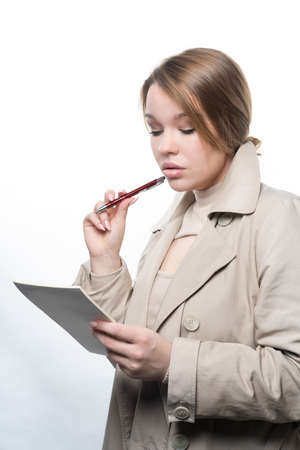 Portrait of a young girl, with long hair, holding a notebook and a pen in her hands Studio, white backgroundの写真素材