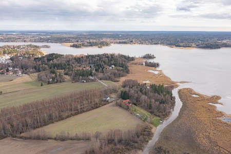 Photo from the drone. a narrow river flows into the bay. Finland. Scandinavian nature in early spring. Yellow grass in the fields. There are a lot of reeds in the bay.の写真素材