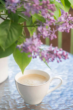 On the table a bouquet of lilacs and a cup of coffee Concept, relaxation